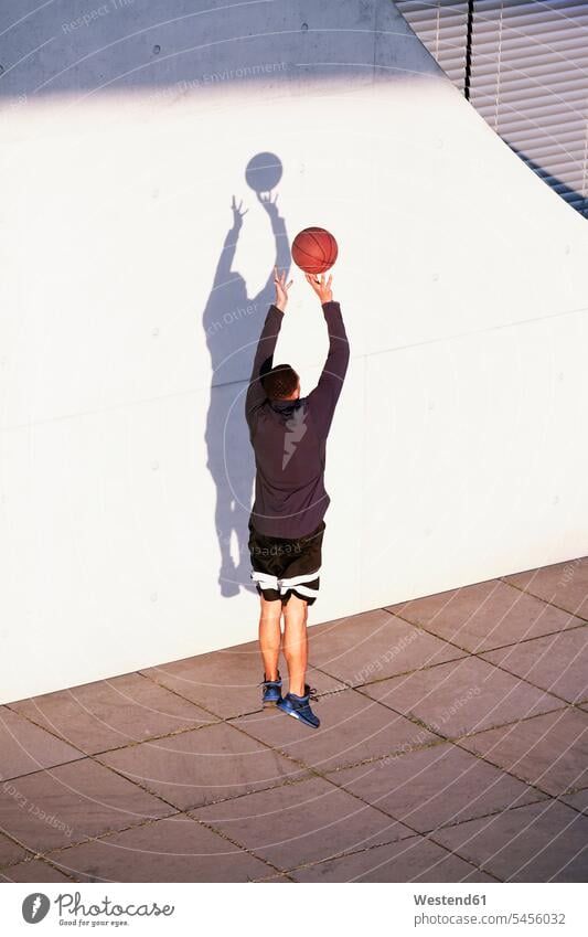 Young man playing basketball in the city men males throwing exercising exercise training practising basketballs Adults grown-ups grownups adult people persons