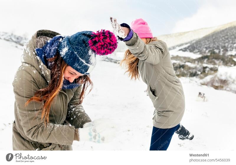 Friens having a snowball fight in the snow friendship laughing Laughter winter hibernal snowball fights female friends playing weather positive Emotion Feeling