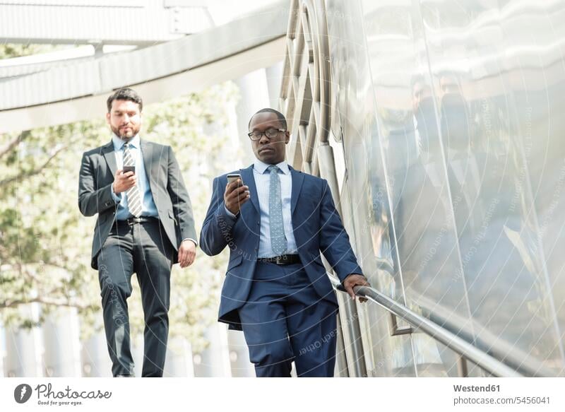 Two businessmen on the move looking at cell phones Businessman Business man Businessmen Business men mobile phone mobiles mobile phones Cellphone