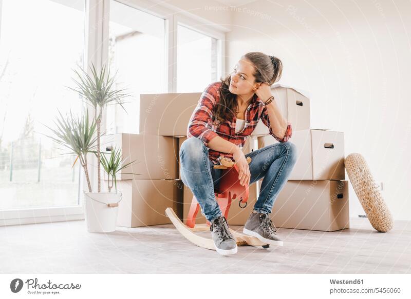 Mature woman moving house, sitting on rocking horse females women Seated property owner owners flat flats apartment apartments move Moving Home Adults grown-ups