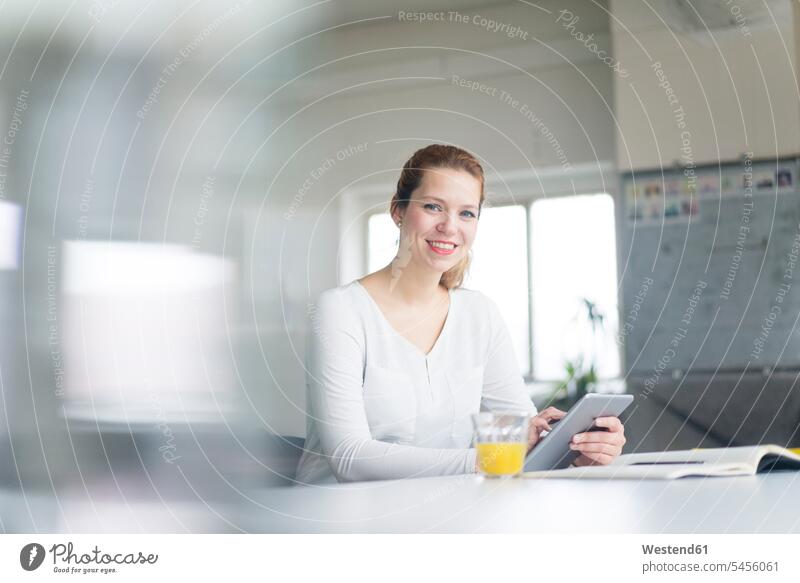 Businesswoman working at desk in her office, using digital tablet sitting Seated happiness happy businesswoman businesswomen business woman business women