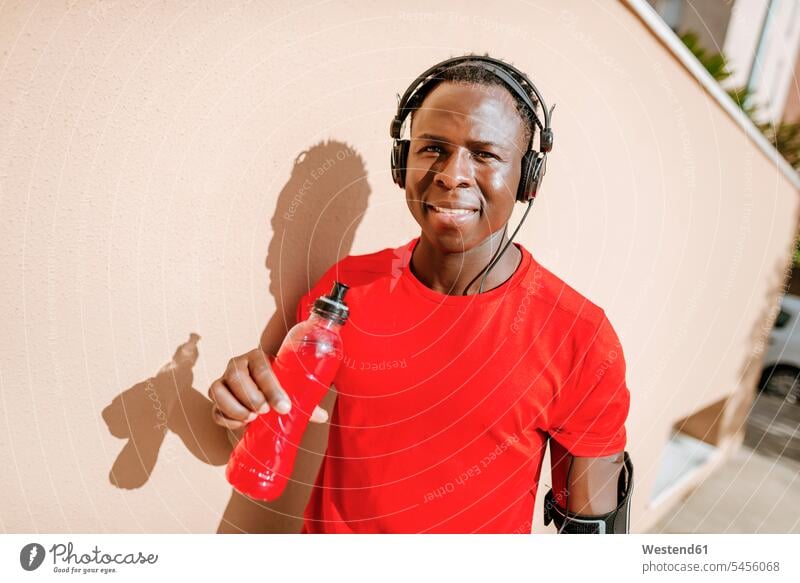 Portrait of man with isotonic drink in sportswear listening music with headphones men males portrait portraits headset Adults grown-ups grownups adult people