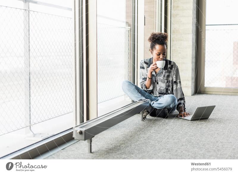 Young woman sitting on floor using laptop, drinking coffee Coffee working At Work office offices office room office rooms confidence confident young females
