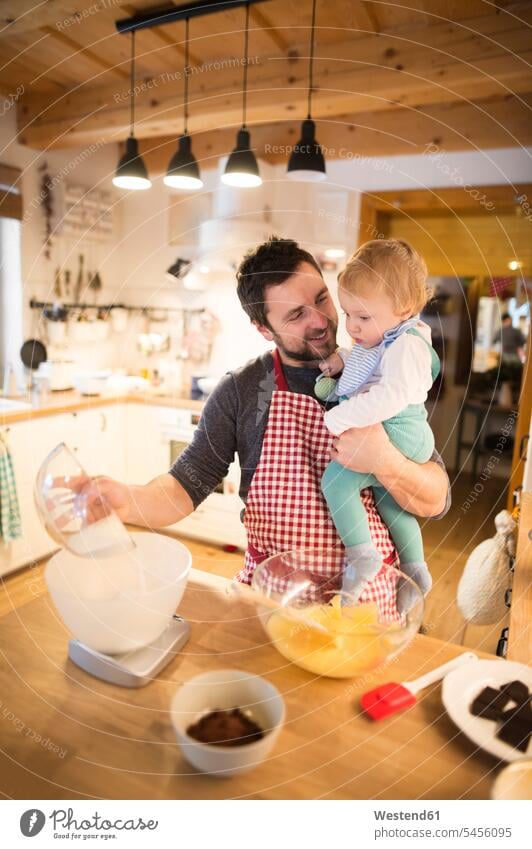Father and baby boy in kitchen baking a cake carrying stirring father pa fathers daddy dads papa dough son sons manchild manchildren pies cakes bake ingredient