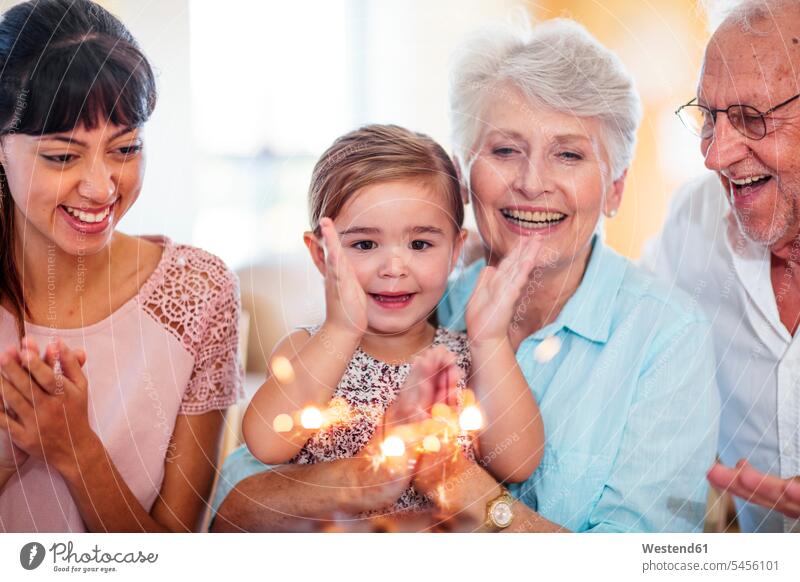 Little girl lwatching sparklers on a birthday cake, sitting on grandmother's lap Wish Wishes wishing granddaughter granddaughters Birthday cake Birthday cakes