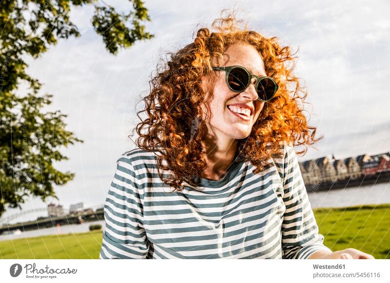 Germany, Cologne, portrait of laughing redheaded young woman wearing sunglasses portraits females women Adults grown-ups grownups adult people persons