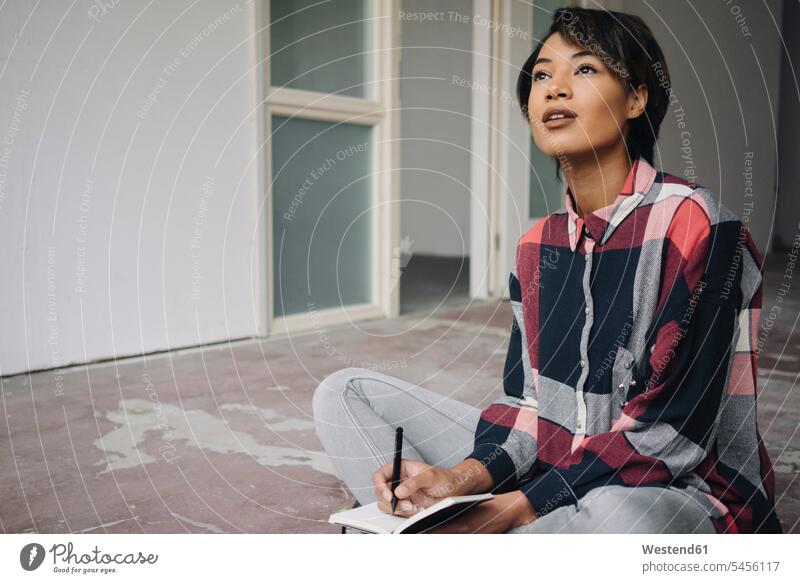 Woman sitting on cracked floor with notebook writing write businesswoman businesswomen business woman business women females notebooks business people