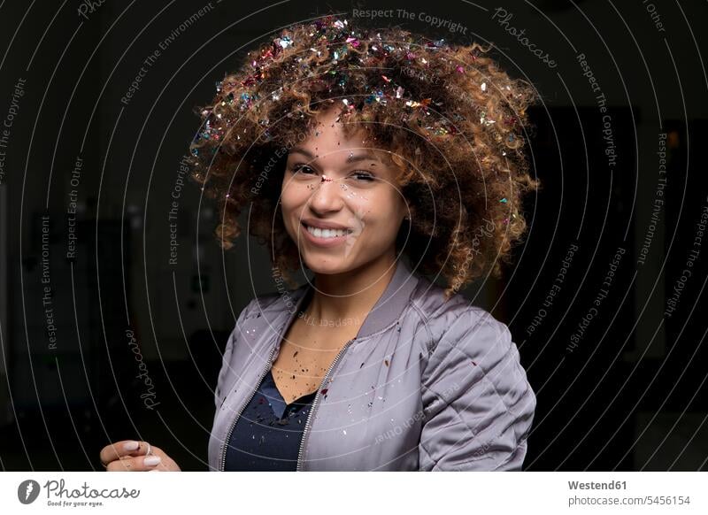 Portrait of laughing woman with confetti on her hair against dark background portrait portraits females women Laughter people persons human being humans