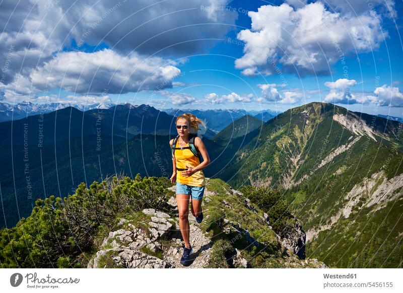 Germany, Bavaria, Young woman running in the mountains females women mountain range mountain ranges nature natural world jogger joggers female jogger Adults