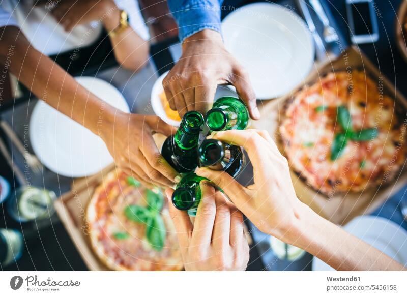 Group of friends having pizza and beer at home Table Tables Pizza Pizzas Beer Beers Ale eating toasting clinking cheers Food foods food and drink Nutrition