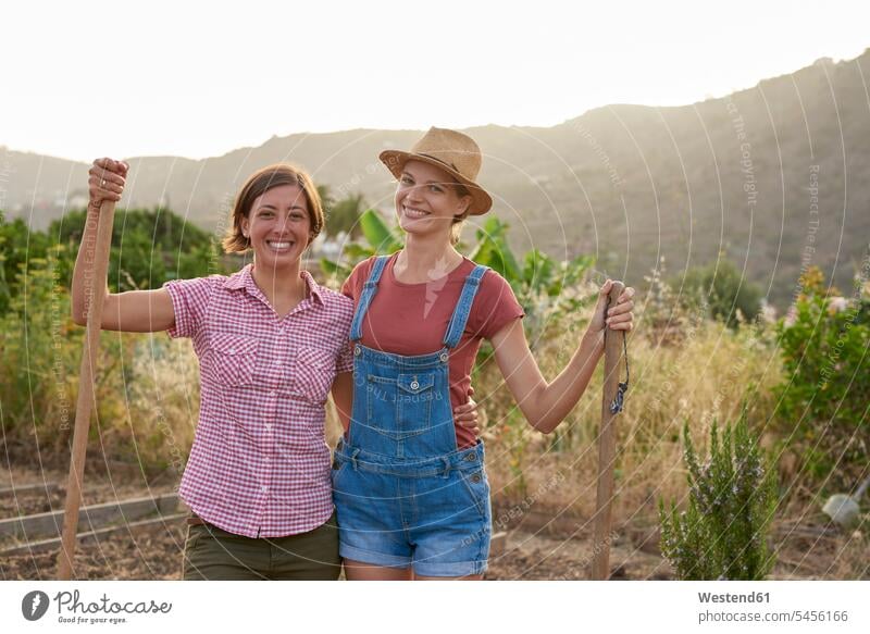 Portrait of two happy farmers with shovels portrait portraits friends friendship gardening yardwork yard work woman females women female friends smiling smile