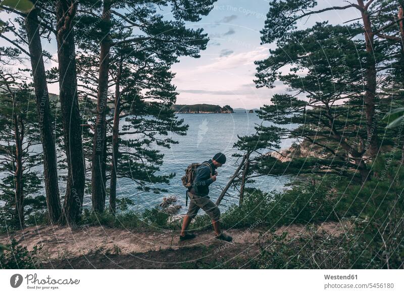 Russia, Far East, Khasanskiy, Japanese sea, man hiking at Telyakovsky bay ocean hike men males hiker wanderers hikers water waters body of water Adults