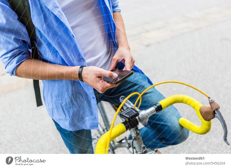 Young man with racing cycle using cell phone, partial view cyclist people persons human being humans human beings riding bicycle riding bike bike riding cycling