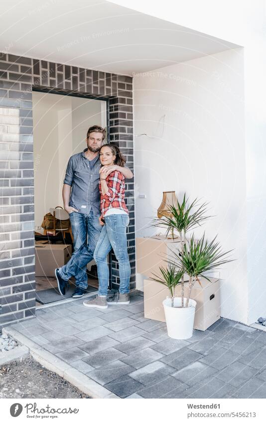 Happy couple standing in door of their new home building property flat flats apartment apartments owner owners twosomes partnership couples moving house move