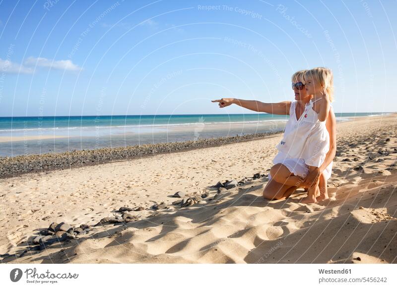 Spain, Fuerteventura, mother with daughter on the beach daughters mommy mothers ma mummy mama pointing point at pointing at show showing beaches child children
