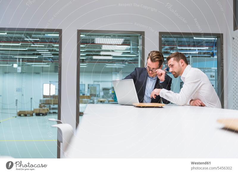 Two businessmen sitting in modern office, discussing in front of laptop colleagues team Businessman Business man Businessmen Business men work meeting briefing