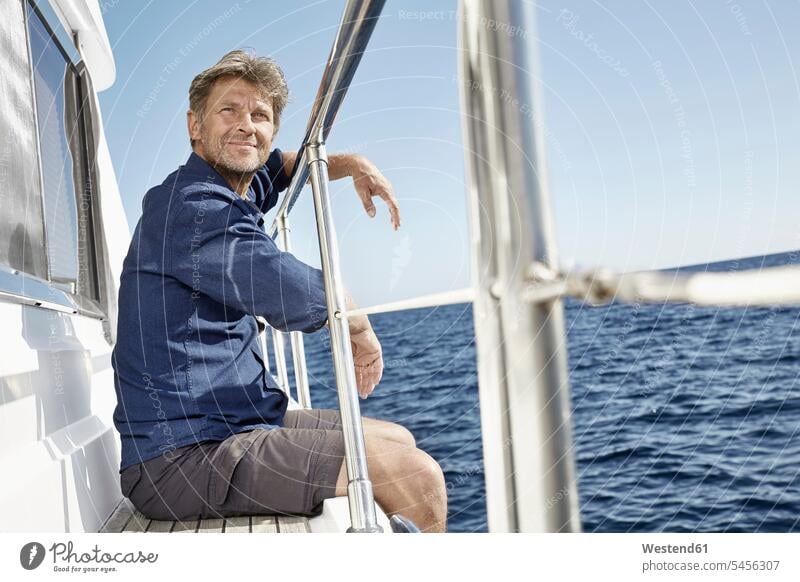 Portrait of content mature man sitting on his motor yacht men males portrait portraits motor yachts Adults grown-ups grownups adult people persons human being