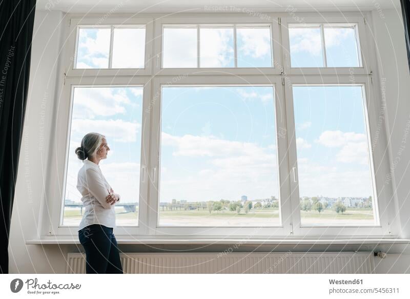 Businesswoman in office looking out of window offices office room office rooms businesswoman businesswomen business woman business women standing windows