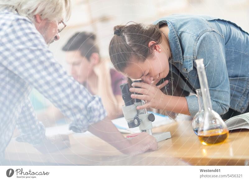 Science student with teacher in class looking through microscope schoolgirl female pupils School Girl schoolgirls School Girls microscopes learning education
