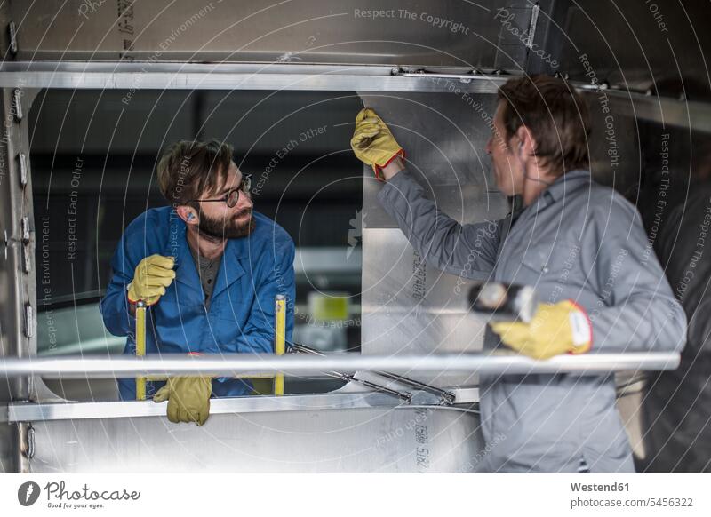 Two men discussing inside of steel container in factory working At Work colleagues man males Adults grown-ups grownups adult people persons human being humans