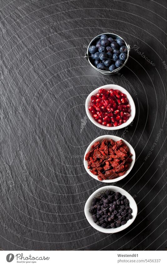 Bowls of blueberries, pomegranate seed, goji berries and chokeberries on slate food and drink Nutrition Alimentation Food and Drinks arrangement grouping
