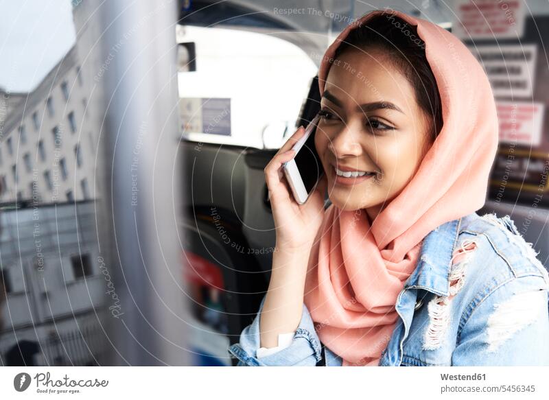 UK, England, London, young woman wearing hijab on the phone in a taxi mobile phone mobiles mobile phones Cellphone cell phone cell phones Muslim Taxies call
