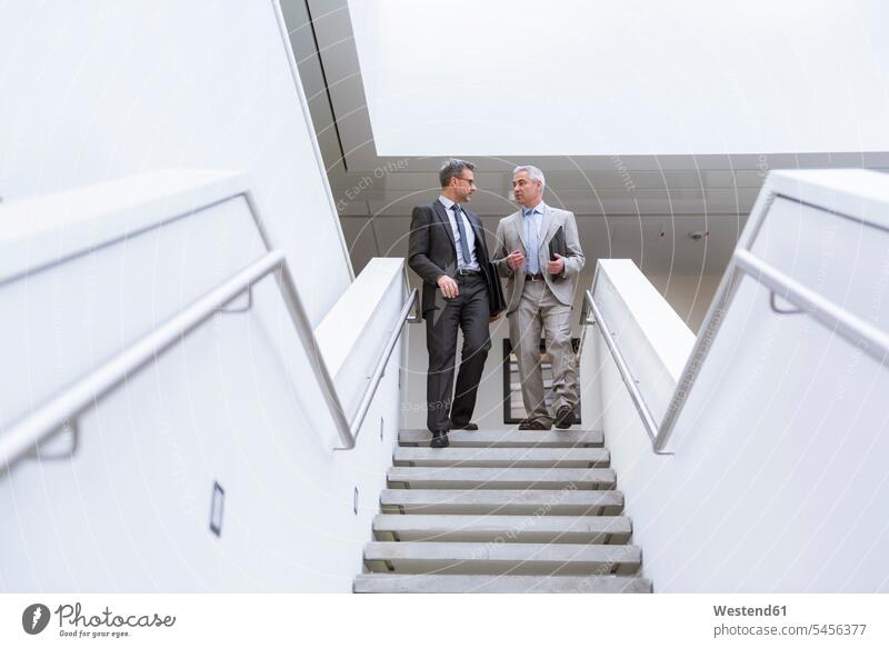Two businessmen having an informal meeting Businessman Business man Businessmen Business men stairs stairway walking going together expertise competence