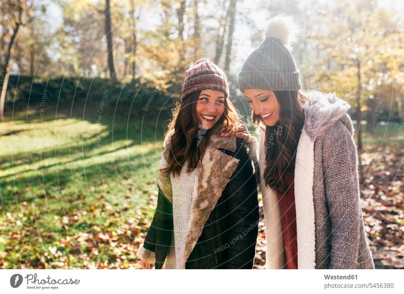 Two pretty women walking in an autumnal forest female friends smiling smile woman females woods forests fall beautiful going mate friendship Adults grown-ups