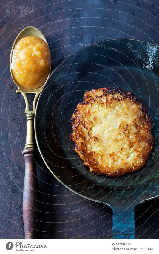 Potato fritter in frying pan and spoon of apple sauce old hearty savoury food lusty Frying pan frying pans ready to eat ready-to-eat Potato Pancake