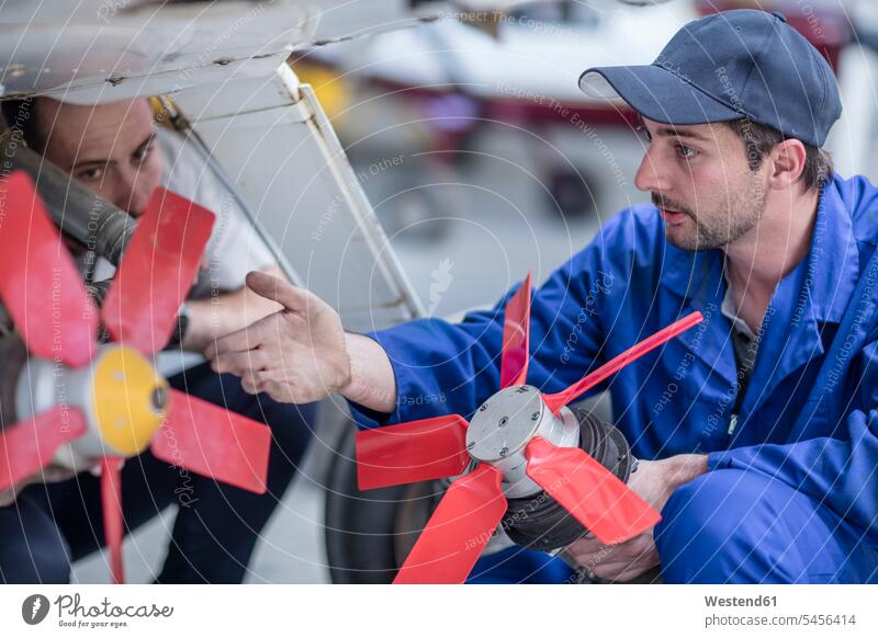 Mechanics in hangar repairing light aircraft airplane aeroplanes airplanes mechanic mechanician repairman mechanicians mechanists repairmen mechanics machinists