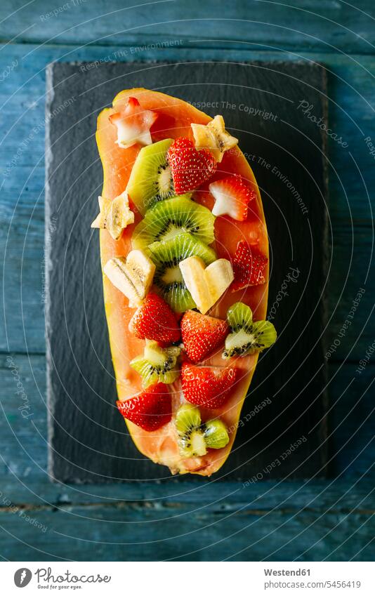 Half papaya with pieces of banana, kiwi and strawberries garnished Fruit Fruits healthy eating nutrition blue wood wooden half halves halved sliced vitamines