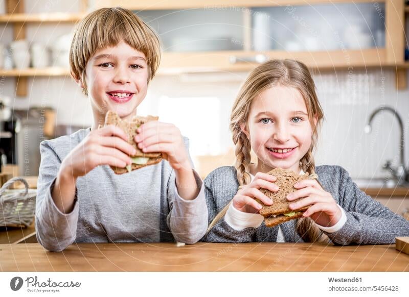 Brother and sister eating a sandwich smiling smile brother brothers Sandwich Sandwiches kitchen domestic kitchen kitchens sisters siblings brother and sister