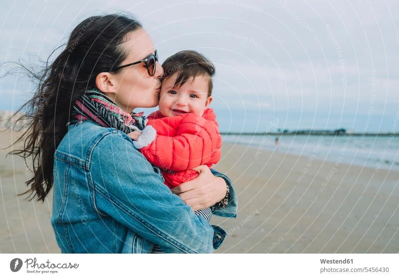 Portrait of smiling baby girl on her mother's arms on the beach mommy mothers ma mummy mama infants nurselings babies beaches baby girls female parents family