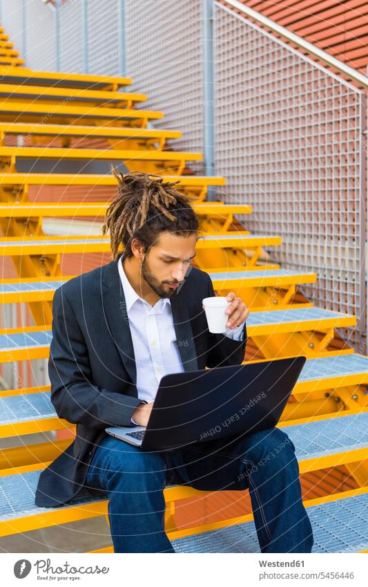 Young businessman with dreadlocks sitting on stairs using laptop Businessman Business man Businessmen Business men Laptop Computers laptops notebook