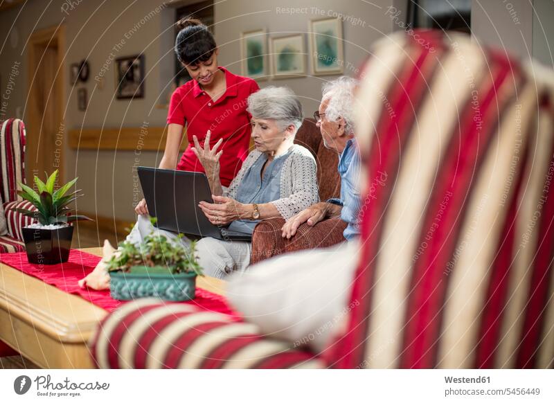 Seniors at retirement home looking at photo albums laptop Laptop Computers laptops notebook elderly care geriatric care nursing home Curiosity Curious