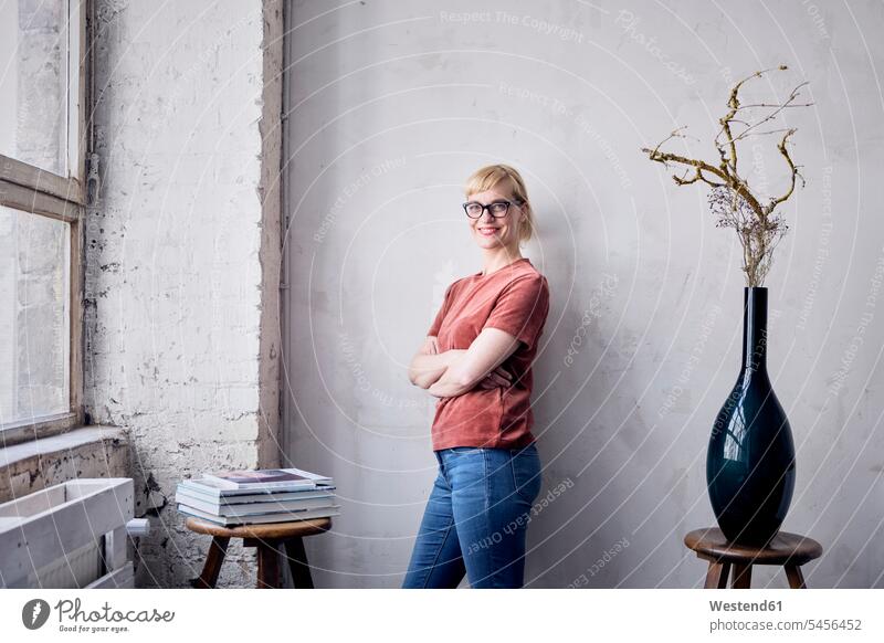Portrait of smiling woman leaning against wall in loft freelancer freelancing lofts standing creative professional Creative People creatives Creative Occupation