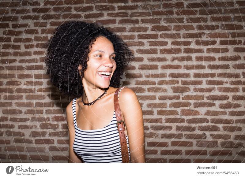 Portrait of laughing woman in front of brick wall at night Laughter portrait portraits females women positive Emotion Feeling Feelings Sentiments Emotions