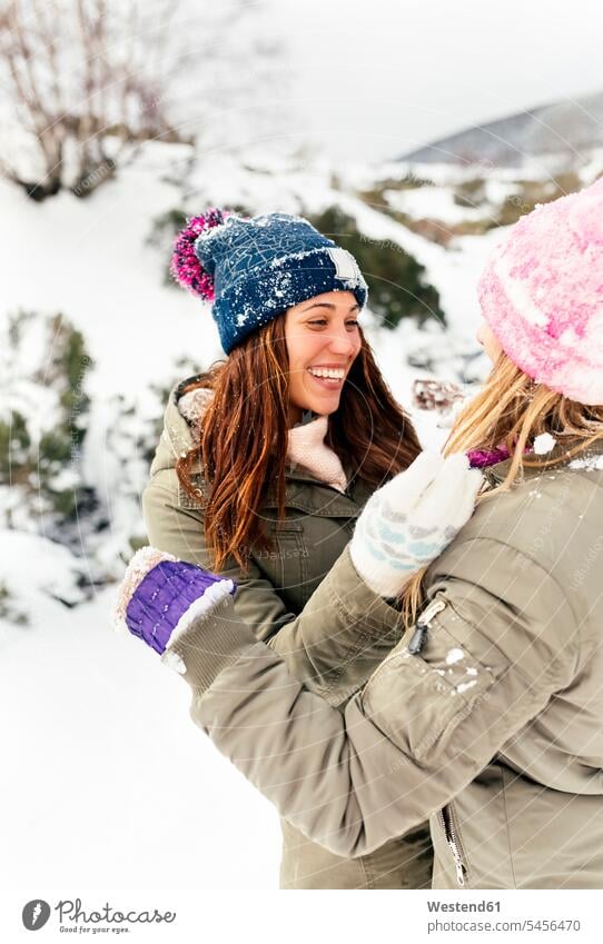 Two friends having fun in the snow friendship playing female friends winter hibernal laughing Laughter mate weather positive Emotion Feeling Feelings Sentiments