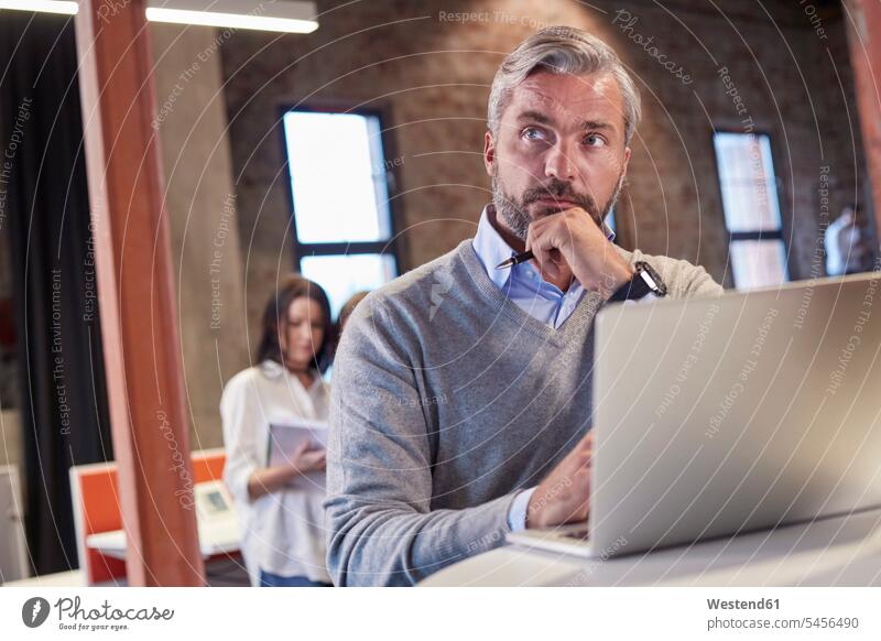 Mature man sitting at laptop, thinking Laptop Computers laptops notebook Seated working At Work office offices office room office rooms using laptop