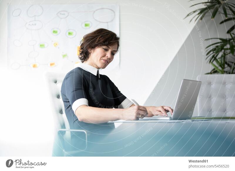 Businesswoman using laptop in office businesswoman businesswomen business woman business women Laptop Computers laptops notebook business people businesspeople