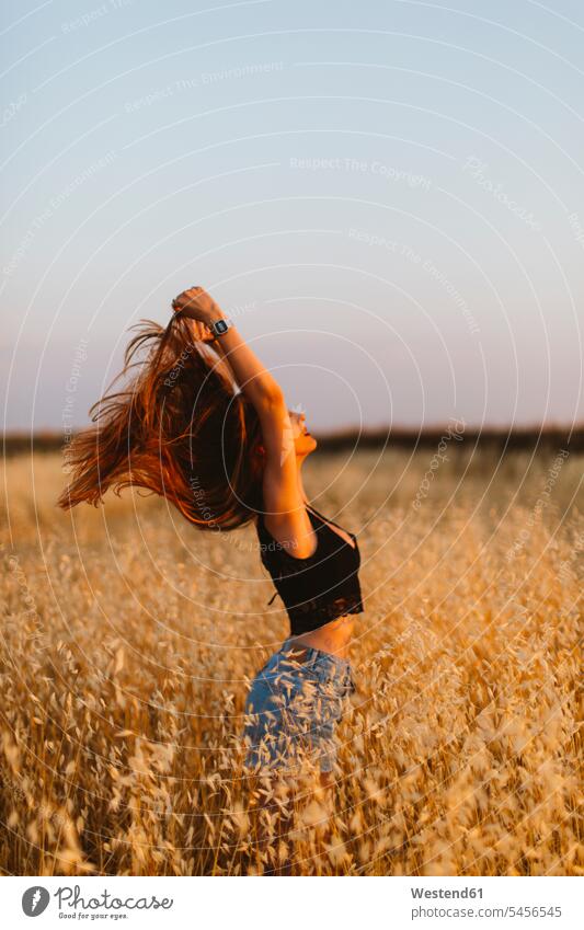 Young woman standing in grain field enjoying sunset females women Adults grown-ups grownups adult people persons human being humans human beings indulgence