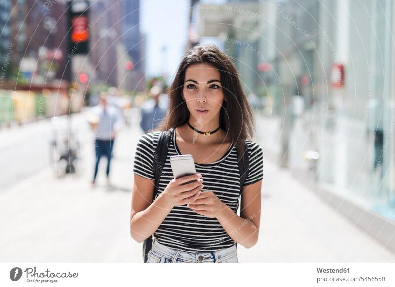 USA, New York City, young woman holding cell phone in Manhattan females women mobile phone mobiles mobile phones Cellphone cell phones Adults grown-ups grownups