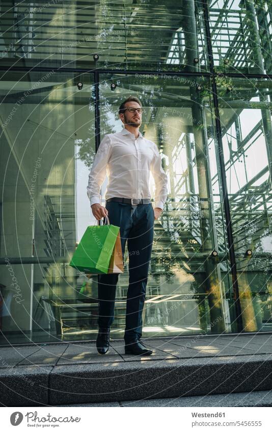 Businessman holding paper bags in front of building business life business world business person businesspeople Business man Business men Businessmen