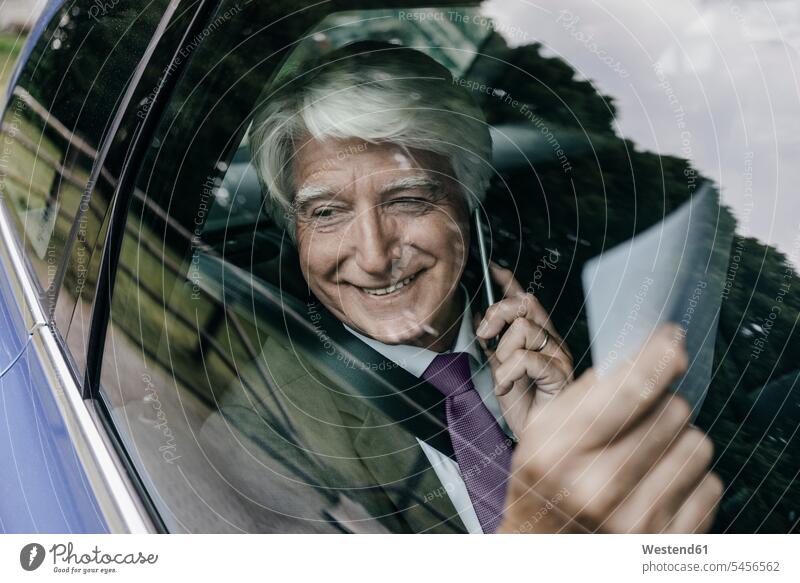 Smiling senior businessman with documents on the phone in a car Businessman Business man Businessmen Business men call telephoning On The Telephone calling