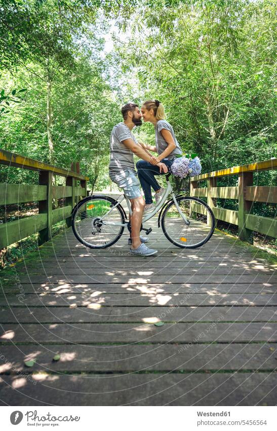 Couple with bicycle about to kiss on a wooden walkway in the countryside couple twosomes partnership couples path trail paths bikes bicycles kissing kisses