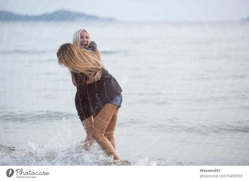Two young women having fun in the sea Fun funny female friends ocean couple twosomes partnership couples laughing Laughter happiness happy mate friendship water