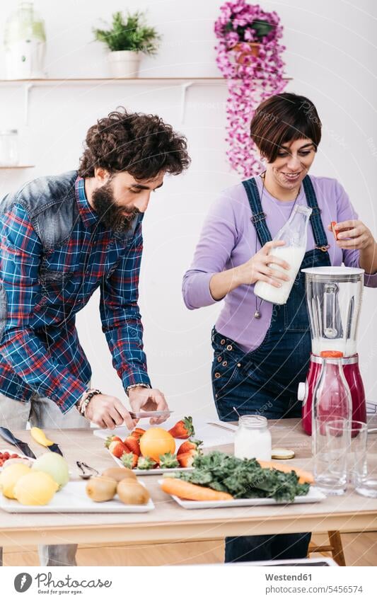 Couple preparing smoothies with fresh fruits and vegetables Smoothies Food Preparation preparing food couple twosomes partnership couples Drink beverages Drinks