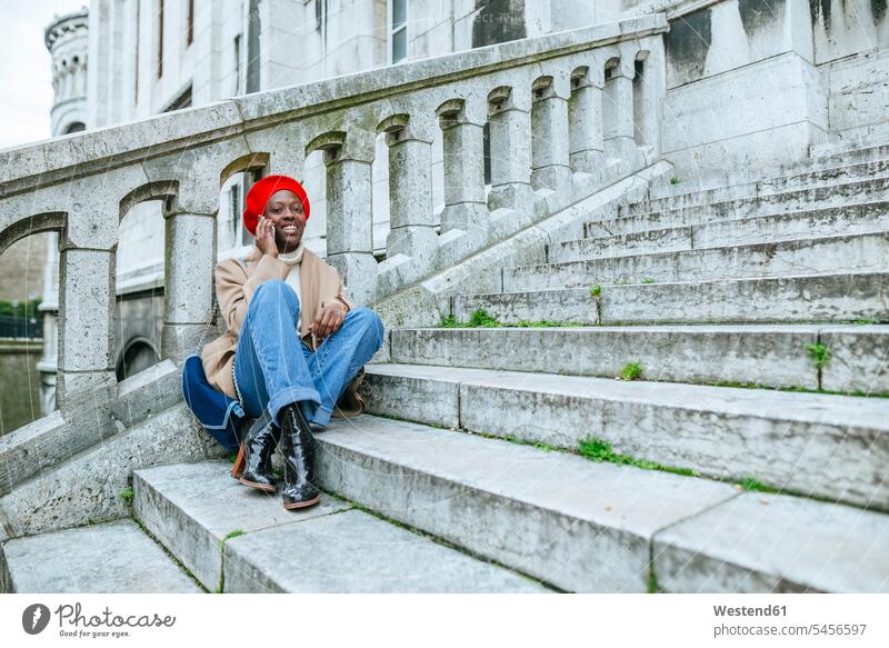 Young woman in Paris sitting on stairs, talking on the phone females women Sacre Coeur stairway solo traveler single traveller solo traveller single traveler