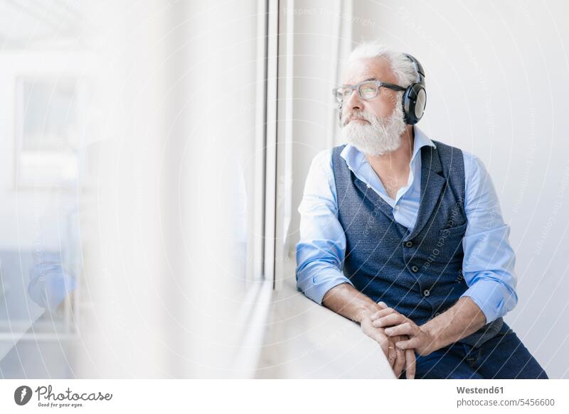 Mature man wearing glasses and headphones looking out of window portrait portraits hearing headset windows men males Adults grown-ups grownups adult people