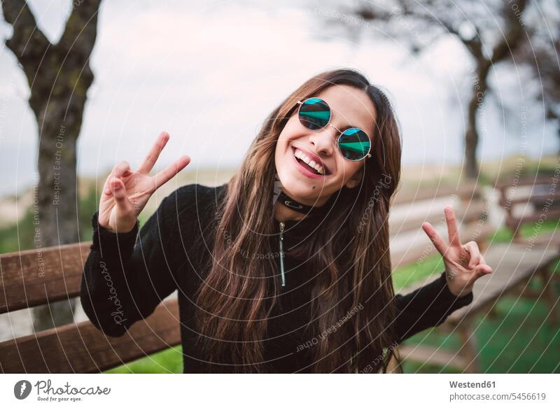Portrait of young woman wearing mirrored sunglasses showing victory signs sun glasses Pair Of Sunglasses portrait portraits females women Adults grown-ups
